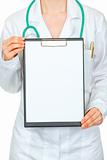 Medical female doctor holding blank clipboard in hands. Close-up.
