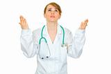 Frustrated medical doctor woman looking up and  raising her hands
