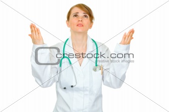 Frustrated medical doctor woman looking up and  raising her hands
