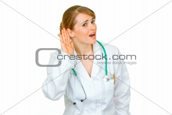 Speak loud! Stressful medical doctor woman holding hand at ear and listening

