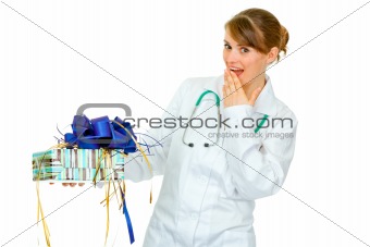 Surprised medical doctor woman holding present in hand 
