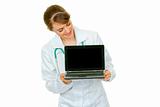 Smiling  medical doctor woman looking on laptop with blank screen
