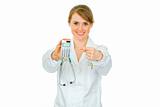 Smiling  medical doctor woman pointing finger on calculator
