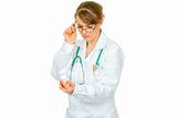 Concentrated medical female doctor in eyeglasses reading name of drug
