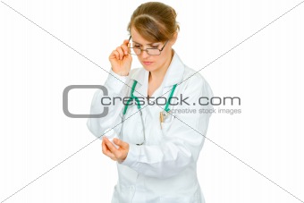 Concentrated medical female doctor in eyeglasses reading name of drug
