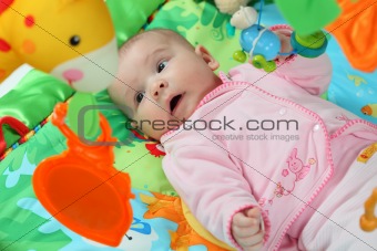 Little baby playing on a colorful jungle blanket