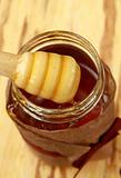 jar with honey and wooden spoon for honey on a brown background