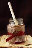 jar with honey and wooden spoon for honey on a brown background