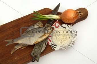 Dried fish, rnife, onions and salt on a board