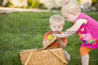 Cute Brother and Sister Toddlers Playing with Apple and Picnic Basket in the Park.