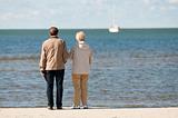 elderly couple on seashore looking boat at the sea