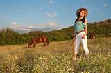 girl cowboy standing in a field with a horse