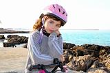 bicycle little pensive girl pink helmet in rocky beach