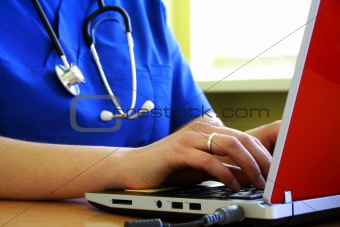 Doctor sitting at  desk with laptop computer