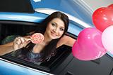Young woman with candy and heart baloons with New car
