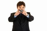Concentrated businessman holding camera in hands and making shot 
