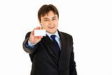 Smiling modern businessman holding blank business card
