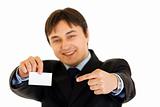 Smiling modern businessman pointing finger at blank business card
