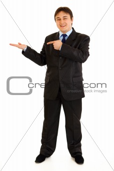 Full length portrait of smiling modern businessman pointing finger on empty hand
