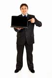 Full length portrait of smiling modern businessman pointing finger on laptops blank screen
