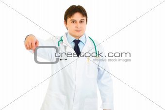Smiling young medical doctor pointing finger down
