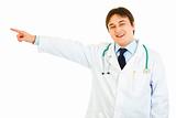 Smiling medical doctor pointing finger in corner at copy space
