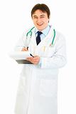 Smiling medical doctor  with stethoscope making notes in document

