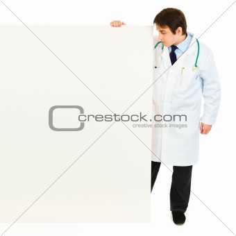 Full length portrait of medical doctor looking at blank billboard
