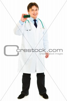 Full length portrait of  smiling medical doctor showsing pack of pills
