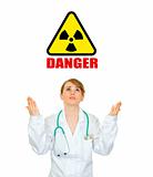 Concept- radiation danger! Frustrated medical doctor woman looking up and  raising her hands
