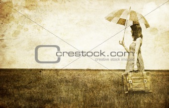 Redhead enchantress with umbrella and suitcase at spring wheat f