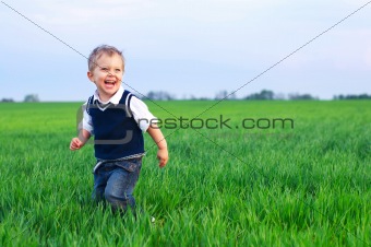 A beautiful little boy runing in the grass