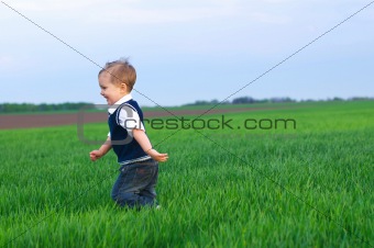 A beautiful little boy runing in the grass