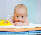 Little cute boy with soap bubbles lying on colorful towels