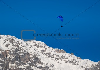 Paraglider flying over snowy mountains