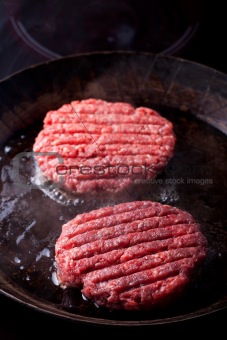 two beef patties in an iron pan