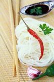 Asian glass noodles, chili pepper and soy sauce on bamboo mat