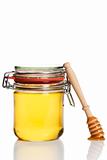 honey covered honey dipper leaning at a honey jar