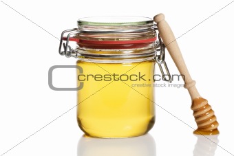 honey covered honey dipper leaning at a honey jar