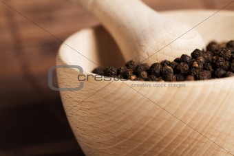 closeup of peppercorns in a wooden mortar