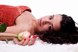 Beautiful woman lying, with a rose, on white, studio shot