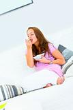Attractive woman sitting on couch and eating muesli
