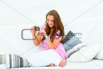 Laughing pretty woman sitting on couch and looking photos in camera
