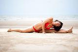 Beautiful woman doing stretches exercise on the beach