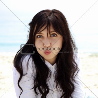 Young beautiful brunette girl lighten up at the beach in spring 