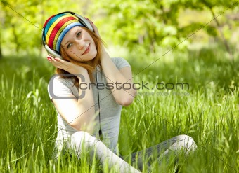 Redhead girl with headphone at green grass.