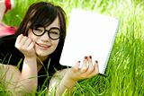 Young teen girl with notebook at green grass.