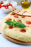 Italian Focaccia bread with tomatoes and basil on a cutting board
