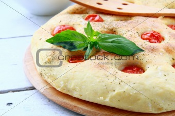 Italian Focaccia bread with tomatoes and basil on a cutting board