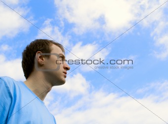 The young man looks at the blue sky